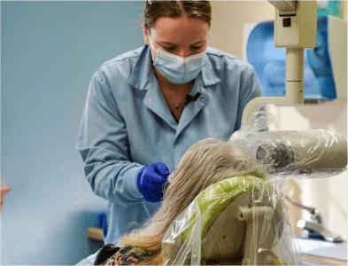 Dr. Eric's female colleague is doing dental work on a patient.