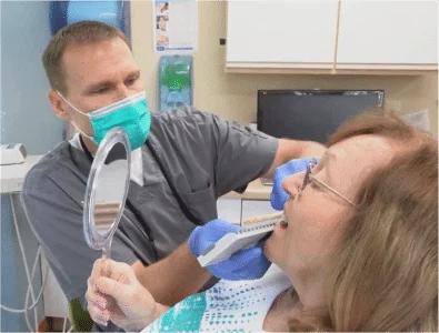 Patient looking into the mirror while Dr. Eric doing dental work