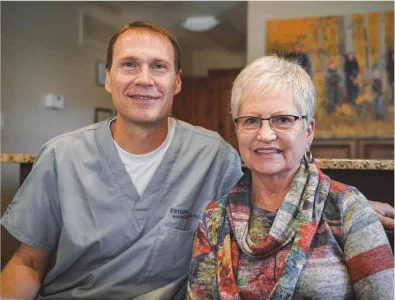 Dr. Eric and his patient are smiling together.